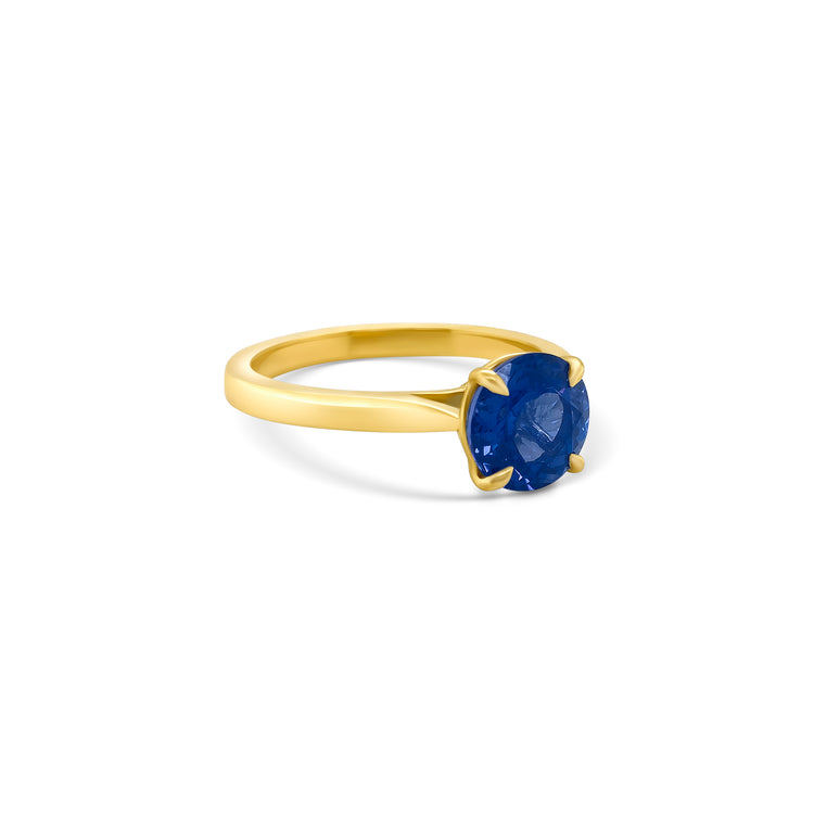 A round solitaire tanzanite ring featuring a brilliant gemstone, perfect for elegant occasions, showcasing timeless beauty, capturing attention with its captivating hue, embodying sophistication and grace, ideal for adding a touch of luxury to any ensemble.