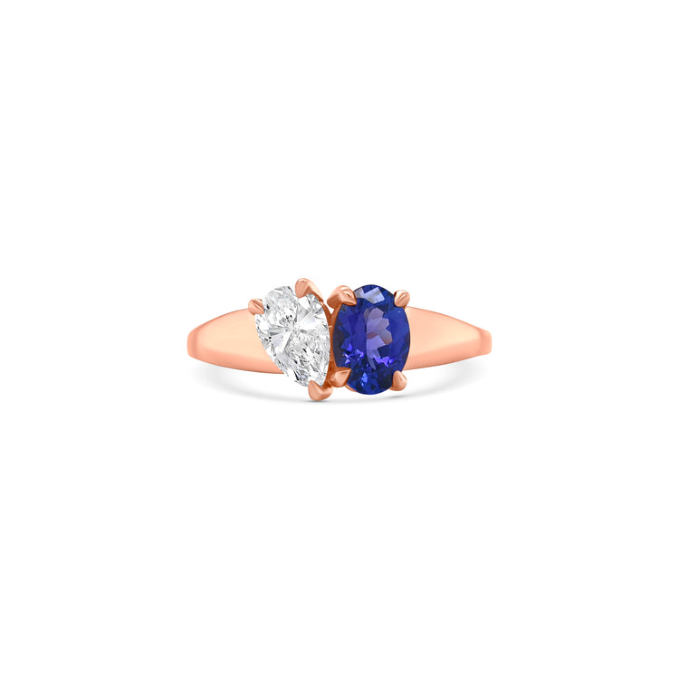 Elegant oval-cut tanzanite ring flanked by sparkling pear-shaped diamonds, set in a polished metal band.