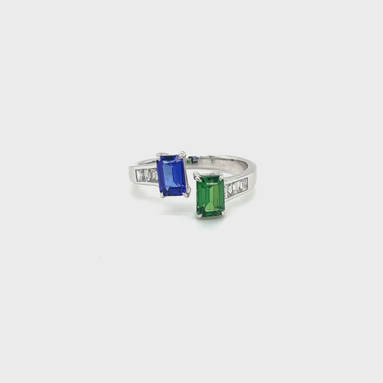 Two stunning gemstones - tsavorite and tanzanite - set in an elegant Toe Et Moi ring. Close-up of the exquisite green tsavorite gemstone in the Toe Et Moi ring. Mesmerizing violet-blue tanzanite gemstone showcased in the luxurious ring design. A side view of the Tsavorite & Tanzanite Ring highlighting the intricate craftsmanship. The Toe Et Moi ring featuring a harmonious blend of tsavorite and tanzanite gemstones.