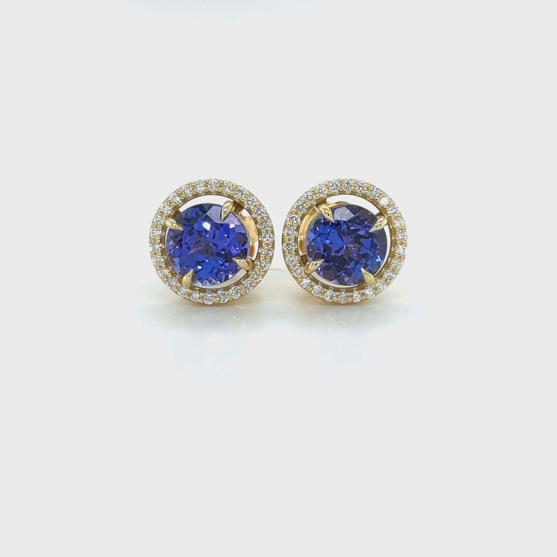 Exquisite round Tanzanite stud earrings, surrounded by a dazzling halo of brilliant diamonds. Elegant jewelry for special occasions, featuring vibrant Tanzanite gems and sparkling diamond accents. Stunning halo design, showcasing the beauty of round Tanzanite stones, complemented by the brilliance of diamonds. Perfect accessories to add a touch of glamour and sophistication to any ensemble