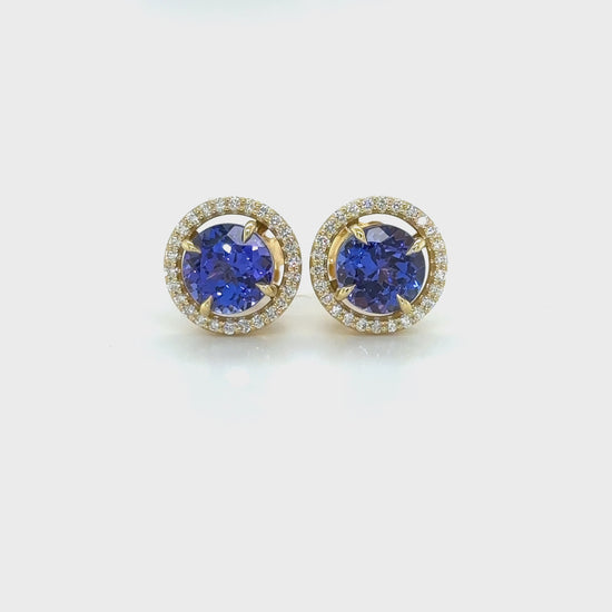 Exquisite round Tanzanite stud earrings, surrounded by a dazzling halo of brilliant diamonds. Elegant jewelry for special occasions, featuring vibrant Tanzanite gems and sparkling diamond accents. Stunning halo design, showcasing the beauty of round Tanzanite stones, complemented by the brilliance of diamonds. Perfect accessories to add a touch of glamour and sophistication to any ensemble