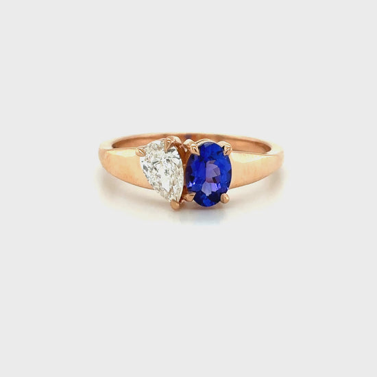Elegant oval-cut tanzanite ring flanked by sparkling pear-shaped diamonds, set in a polished metal band.