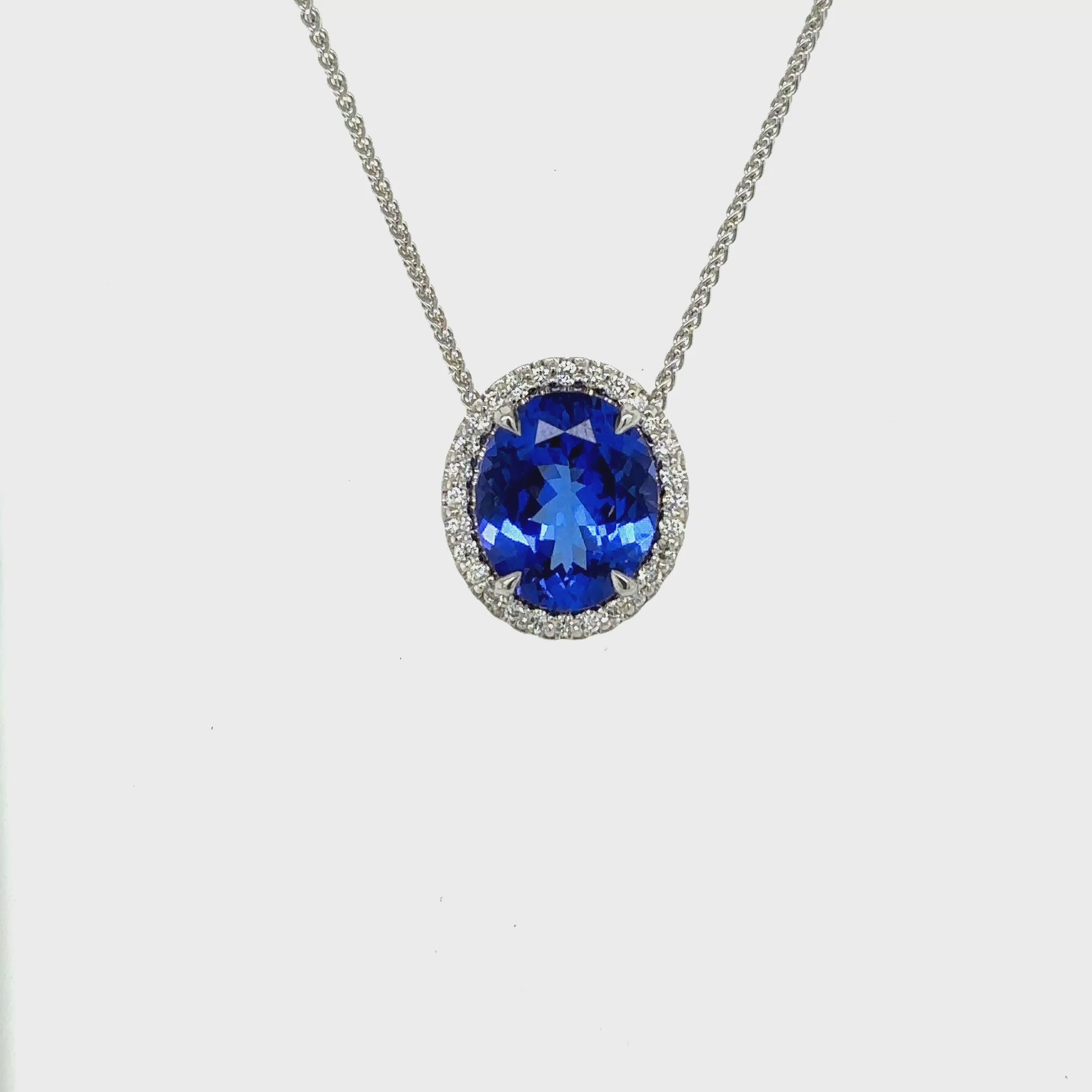 Oval tanzanite and halo diamond necklace, Elegant necklace with oval-cut tanzanite and diamond halo, Luxury halo diamond pendant featuring oval tanzanite center, White gold necklace with oval tanzanite and halo diamonds, Sparkling tanzanite necklace with halo diamond accents, Statement necklace with oval tanzanite surrounded by diamonds, Delicate oval tanzanite pendant with shimmering diamond halo