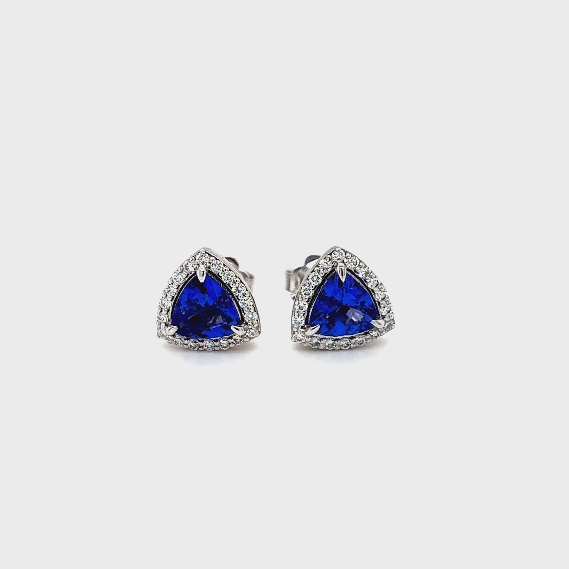 trillion cut tanzanite earrings, tanzanite halo stud earrings, diamond halo gemstone earrings, tanzanite stud earrings, elegant gemstone earrings, luxury tanzanite jewelry, trillion shape halo earrings, fine jewelry earrings, tanzanite and diamond studs, women’s gemstone jewelry