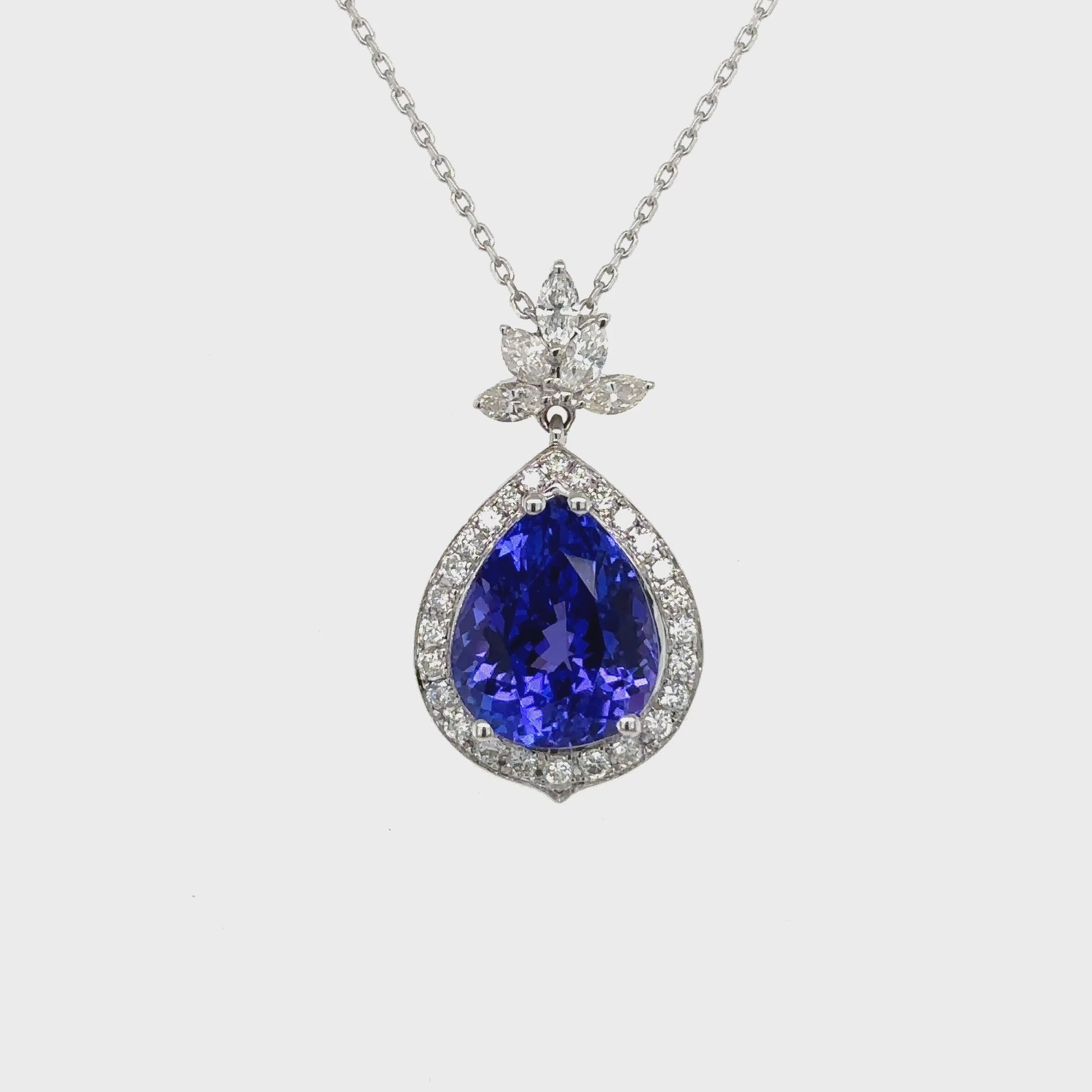 Pear shape tanzanite pendant, tanzanite and diamond halo pendant, pear cut gemstone jewelry, elegant tanzanite necklace, fine jewelry pendant, luxury gemstone necklace, pear cut tanzanite diamond pendant, halo tanzanite pendant necklace, designer gemstone pendant, tanzanite birthstone jewelry.
