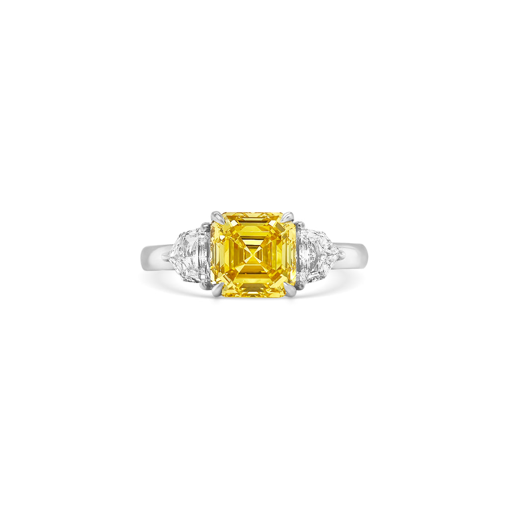 Discover the timeless elegance of this Fancy Yellow Square Emerald Diamond Trilogy Ring, featuring an exquisite yellow emerald-cut diamond and dazzling Cadillac side stones.