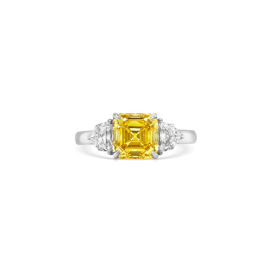 Discover the timeless elegance of this Fancy Yellow Square Emerald Diamond Trilogy Ring, featuring an exquisite yellow emerald-cut diamond and dazzling Cadillac side stones.
