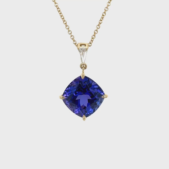 A cushion cut tanzanite pendant, sparkling with diamonds, radiant gemstone jewelry, luxurious tanzanite necklace, dazzling diamond and tanzanite pendant, elegant gemstone pendant, exquisite cushion cut tanzanite and diamond necklace.