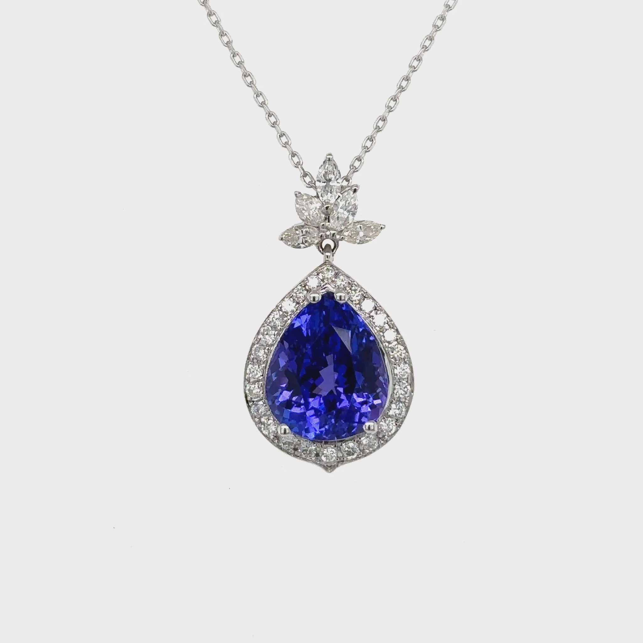 Pear shape tanzanite pendant, tanzanite and diamond halo pendant, pear cut gemstone jewelry, elegant tanzanite necklace, fine jewelry pendant, luxury gemstone necklace, pear cut tanzanite diamond pendant, halo tanzanite pendant necklace, designer gemstone pendant, tanzanite birthstone jewelry.